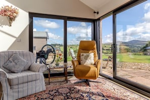 A room with a large window, a sofa, a chair, and a table with a decorative item. - 1 Bed in Cleator (oc-92310) (Ennerdale and Kinniside)
