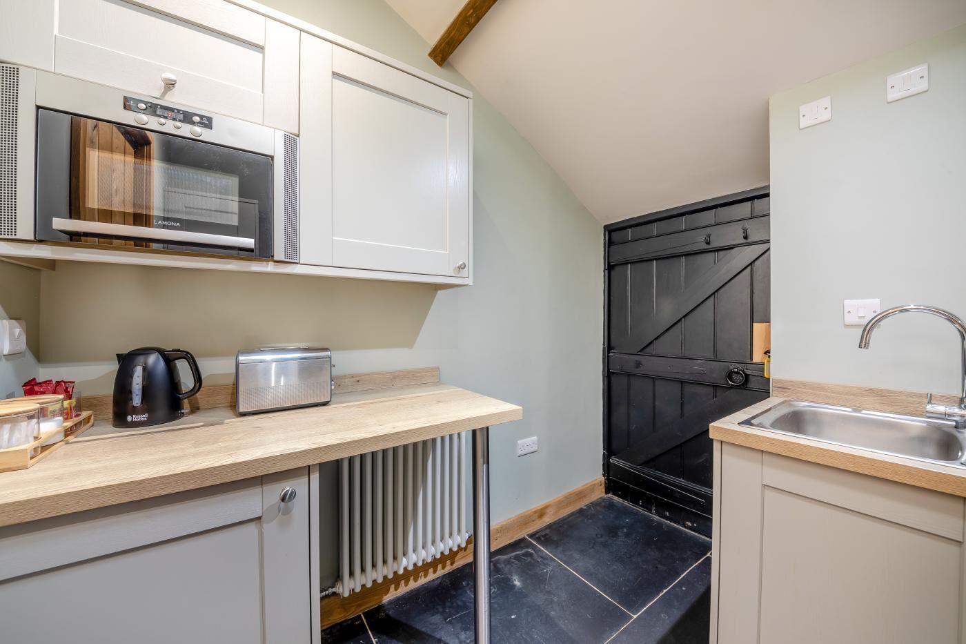 A compact kitchen with a built-in oven, a kettle, and a toaster on the counter.