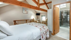 Un dormitorio con cama, escritorio, silla, balcón y zona de ducha.