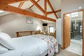 Ein Schlafzimmer mit Bett, Schreibtisch, Stuhl, einem Balkon und einer Dusche.