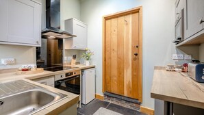 Una cocina funcional con puerta de madera, electrodomésticos de acero inoxidable y una pequeña encimera.