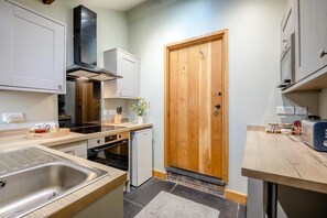 Eine kleine Küche mit Holztür, Edelstahlgeräten und einer Arbeitsplatte.
