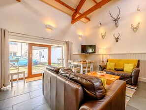 A furnished living room with a leather sofa, a wooden coffee table, and a television mounted on the wall. - 3 Bed in Cleator (oc-88627) (Ennerdale and Kinniside)