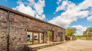 A stone building with a paved driveway and a wooden gate. - 3 Bed in Cleator (oc-88627) (Ennerdale and Kinniside)