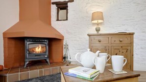 Una habitació acollidora amb una llar de foc, un armari de fusta i una taula amb llibres i tasses.