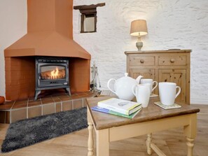 A cozy room with a fireplace, a wooden cabinet, and a table with books and cups. - 1 Bed in Cockermouth (oc-sz358) (Dean)