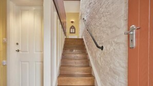 Una escala de fusta amb barana, una porta blanca a la part superior i una paret amb relleu.