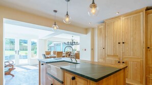 Una cocina amplia con armarios de madera, una isla central e iluminación colgante.
