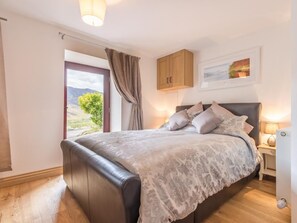 A bedroom with a bed, a nightstand, a window with curtains, a door, and a wall-mounted cabinet. - 2 Bed in Newlands Valley (SZ351) (Borrowdale)