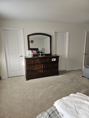 A bedroom with a dark wooden dresser, a mirror, and a bed with a plaid blanket.