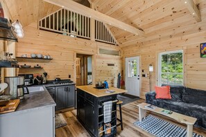 A wooden cabin interior with a kitchen, dining area, and living room.