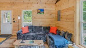Een houten chaletinterieur met een ruime hoekbank, een salontafel en een schilderij aan de muur.