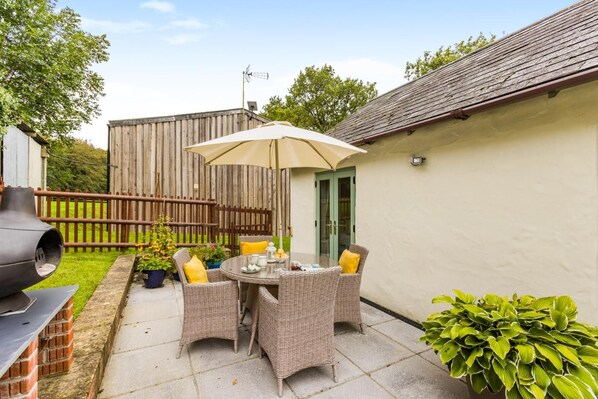 A patio with wicker furniture, a grill, and potted plants.