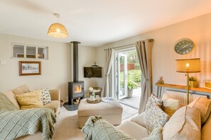 A cozy living room with a fireplace, comfortable seating, and a view of the garden.