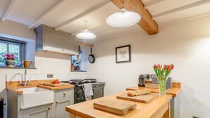 Une cuisine dotée d’un plan de travail en bois, d’une cuisinière et d’un porte-ustensiles suspendu.