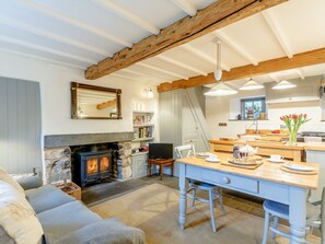 A cozy living room with a fireplace, a dining area with a table set for breakfast, and a kitchen with modern appliances. - 1 Bed in Ullswater (65992) (Glenridding)