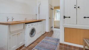 Ein Waschbereich mit Waschmaschine, Holztisch und Schränken.