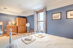 A bedroom with a bed, a wooden wardrobe, a mirror, a fan, and a window with curtains. - 1 Bed in Penrith (oc-sz003) (Penrith)