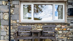 A stone wall with a window, a bench, and a blue pot on the ground. - 1 Bed in Outgate and Tarn Hows (78403) (Outgate)