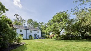 A white house with a well-maintained lawn and trees. - 3 Bed in Windermere (oc-sz596) (Windermere)