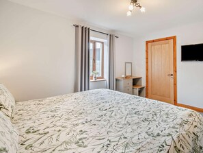 A bedroom with a bed, a dresser, a mirror, a window with curtains, and a television on the wall. - 4 Bed in Forton (oc-81290) (Forton)
