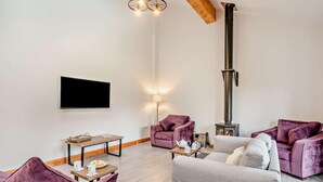 Een woonkamer met een open haard, banken, een salontafel en een televisie.