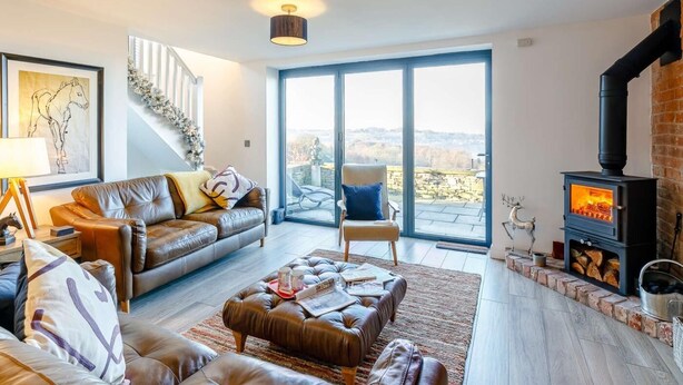 A living room with a sofa, ottoman, and a fireplace. - 2 Bed in Stockport (oc-83789) (Mellor)