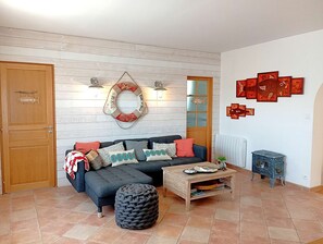 Ein Wohnzimmer mit Sofa, Hocker, Couchtisch und Wanddekorationen.