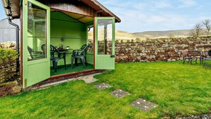 A green outdoor seating area with chairs and a table, a stone wall, and a grassy field. - 2 Bed in Appleby-in-westmorland (oc-91029) (Dufton)