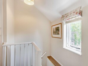 A staircase with a white railing, a framed picture on the wall, and a window with a floral curtain. - 1 Bed in Broadway (oc-broad) (Broadway)
