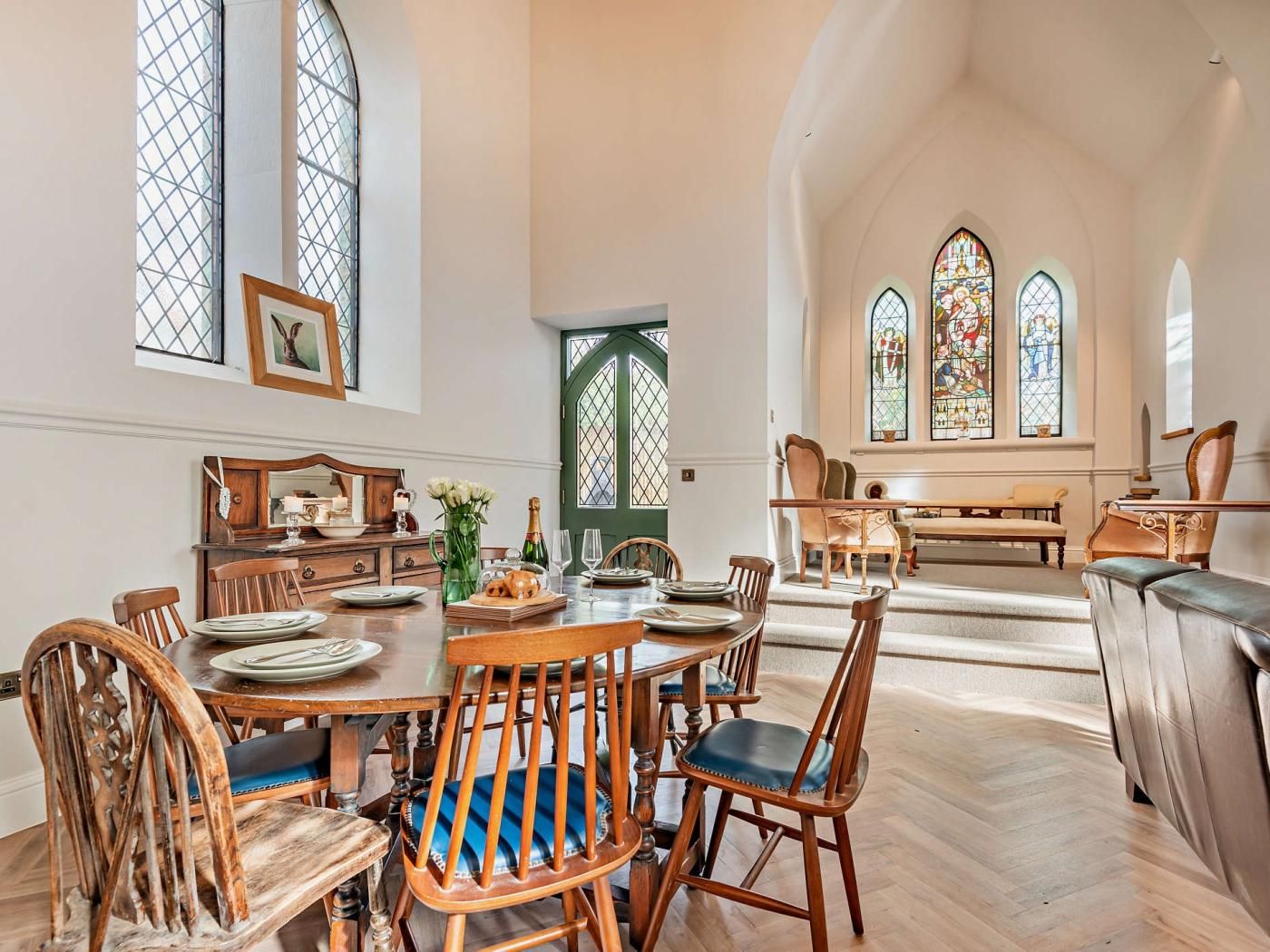 Un espace repas doté d’un plafond haut, de grandes fenêtres et offrant une vue sur l’intérieur d’une église.