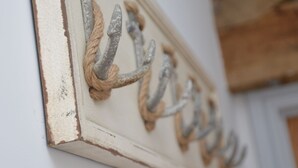 Ein Detailaufnahme eines an der Wand befestigten Metallhakens mit einer Kordel.