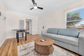 A living room with a sofa, a round coffee table, a foosball table, and a ceiling fan. - Old Town Middle Unit w/ Foosball & BBQ Grill (San Diego)