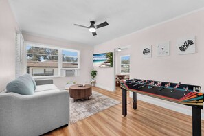 A room with a foosball table, a sofa, a ceiling fan, and a window with blinds. - Old Town Middle Unit w/ Foosball & BBQ Grill (San Diego)
