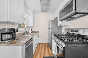 A modern kitchen with stainless steel appliances, white cabinetry, and a granite countertop. - Old Town Middle Unit w/ Foosball & BBQ Grill (San Diego)
