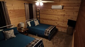 Una cabaña con dos camas, ventilador de techo, calefactor y televisión.