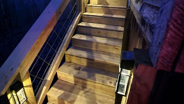 Una escalera de madera con barandilla de metal que lleva a un edificio.