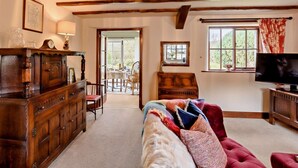 Une pièce avec un plafond en bois, une télévision, un canapé, un meuble en bois et une fenêtre avec des rideaux.