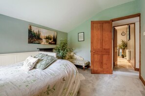 A bedroom with a bed, a sofa, a painting, a door, and a hallway. - 3 Bed in Lydbrook (oc-94490) (Central Lydbrook)