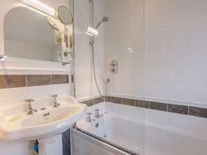 Une salle de bain avec un lavabo blanc, un miroir et une douche.