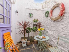 Un petit espace extérieur aménagé avec une table, des chaises et des plantes en pot.
