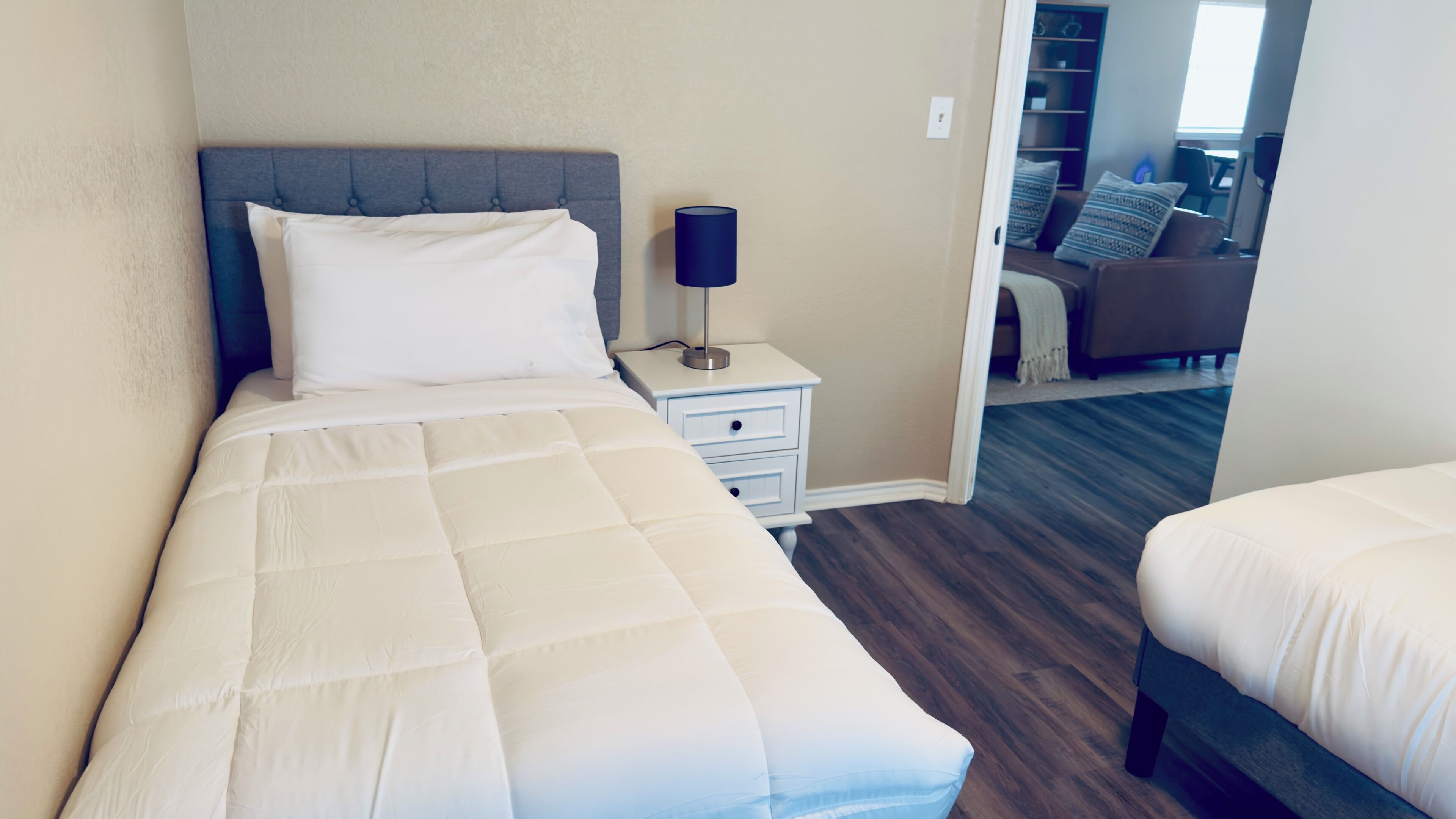 A neatly made bed with a white duvet, a bedside lamp, and a nightstand.