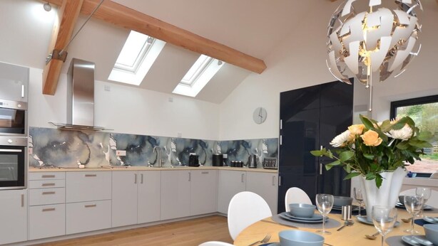 Een moderne keuken met dakramen, een eethoek voor vier personen, en een decoratieve vaas met bloemen.