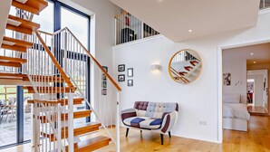 Een modern interieur met een houten trap, een ronde spiegel en een gestreept bankje.