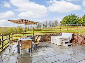 Eine Terrasse im Freien mit Tisch, Stühlen, einem Grill und einer Steinmauer.