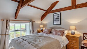 A bedroom with a bed, two bedside tables, a window, and wooden beams on the ceiling. - 3 Bed in Alnwick (oc-94195) (Christon Bank)