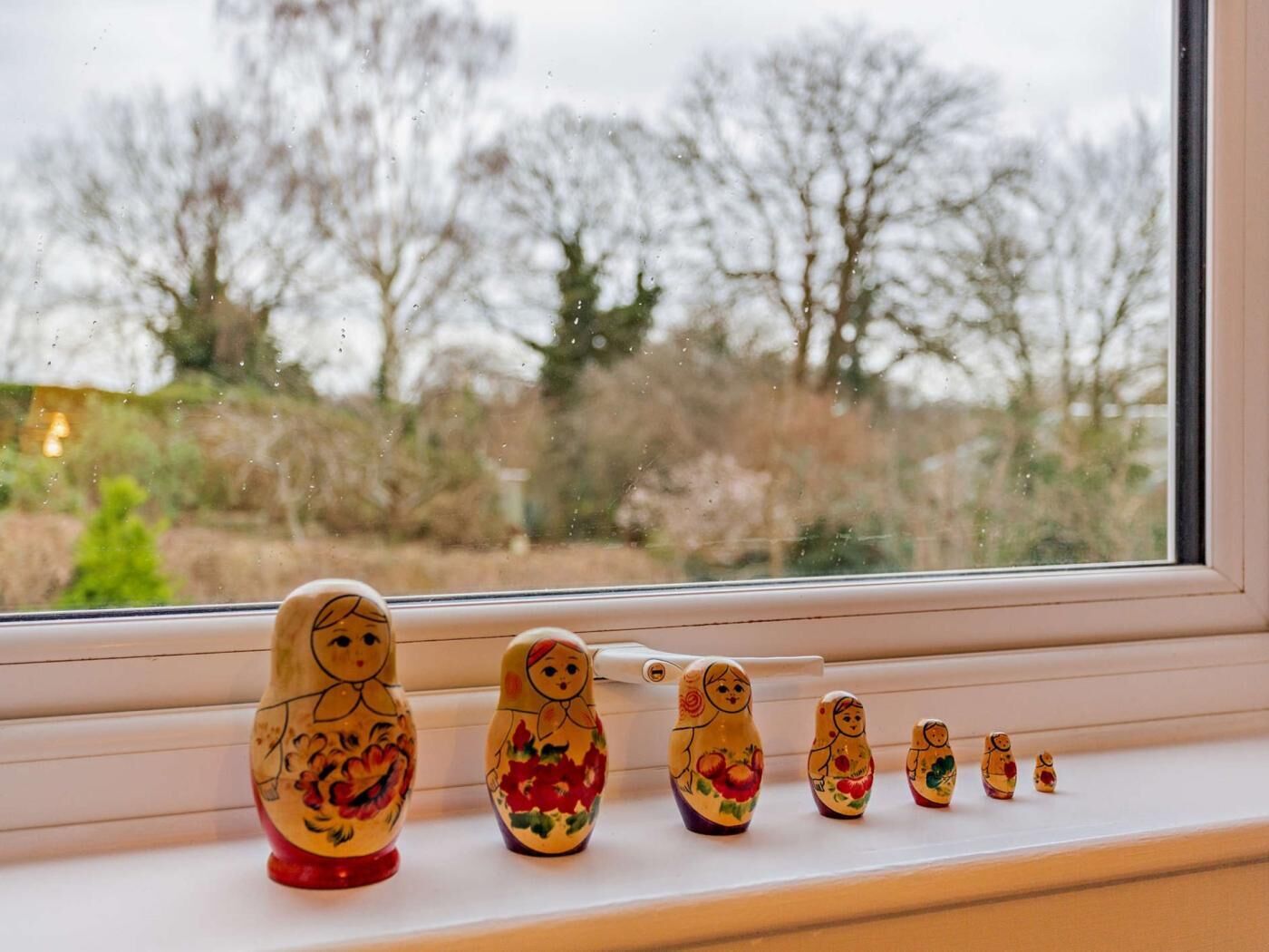A row of matryoshka dolls on a windowsill.