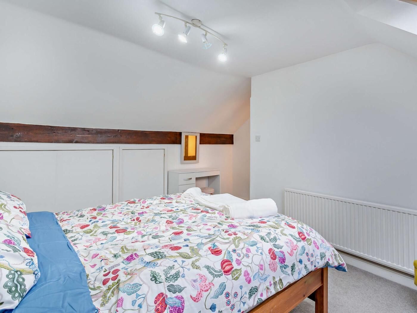A bedroom with a bed, bedside table, and a radiator.