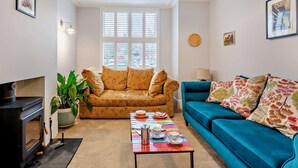 Ein Wohnzimmer mit einer Couch, einem Couchtisch, einem Kamin und einem Fenster mit Jalousien.