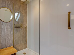 A modern bathroom with a wooden wall, a round mirror, a gold shower handle, and a white sink. - 3 Bed in Grantown-on-spey (oc-94514) (Grantown-on-Spey)